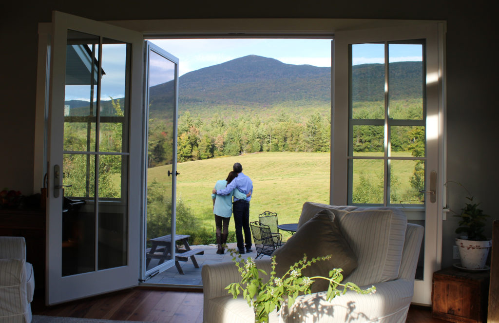 Husband and wife with arms around each other staring out at the mountain in their backyard