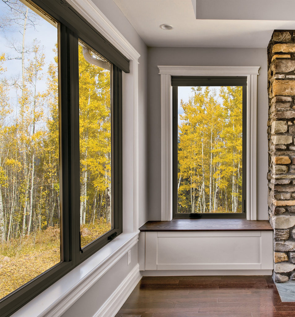 Long living room windows with black frames from the Marvin Essential Collection showing the fall foliage
