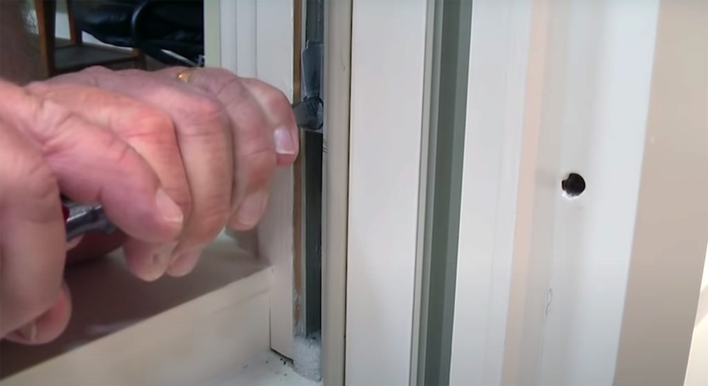 A man's hands showing how to perform clutch foot repair of a Marvin Double Hung Window