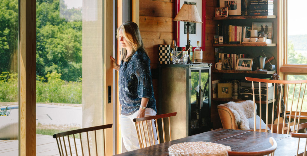 Middle-aged woman pushing open porch sliding door from inside her house