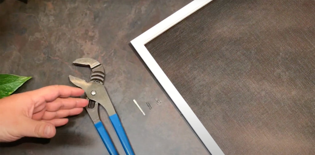 A man's hand with wrench demonstrating how to replace a screen pin on a Marvin Double Hung Window