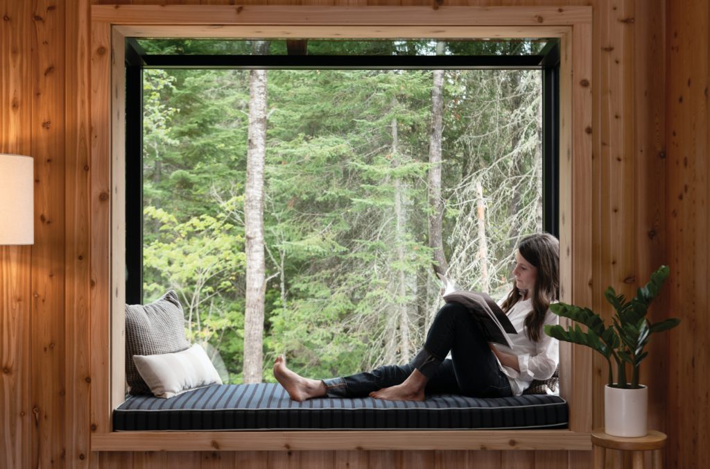 Woman sitting in window box reading a book