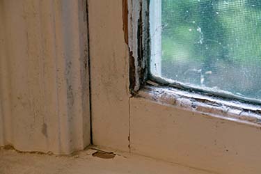 corner of an old window that has paint peeling 